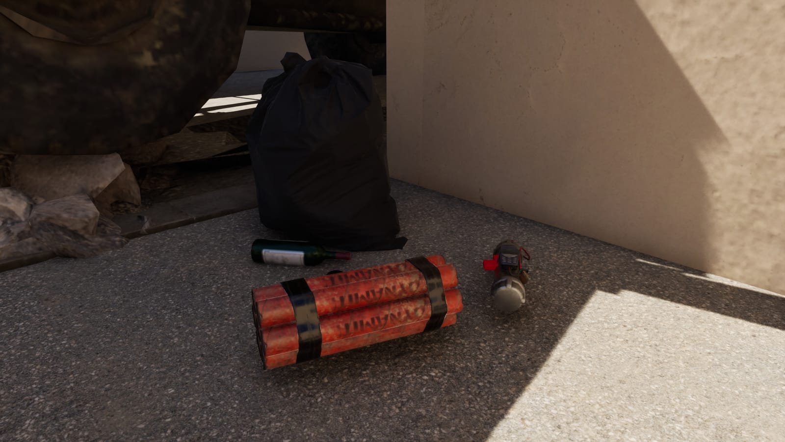 A booby trap at the foot of an armored vehicle: a dynamite bundle and a pipe bomb beside a bag and bottles