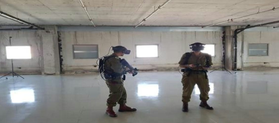 Dos soldados con visores VR entrenando juntos en una nave vacía